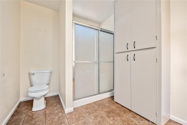 bathroom featuring toilet and a shower with shower door