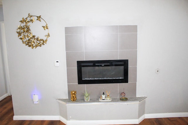 interior details featuring a tiled fireplace and wood-type flooring