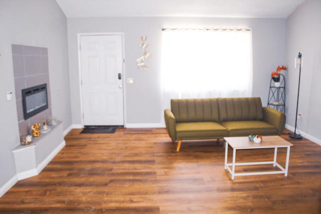 living room featuring lofted ceiling, dark wood-type flooring, and a tile fireplace