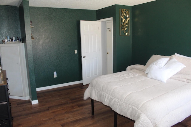 bedroom with dark hardwood / wood-style floors and a textured ceiling