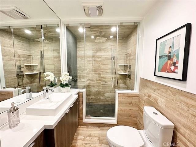 bathroom with vanity, toilet, an enclosed shower, and tile walls