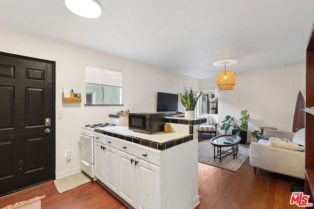 kitchen featuring dark wood-type flooring, white cabinets, kitchen peninsula, white gas range, and tile countertops