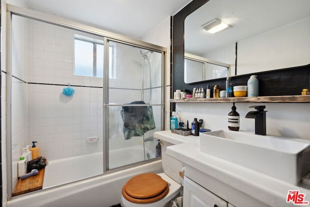 full bathroom with enclosed tub / shower combo, vanity, and toilet