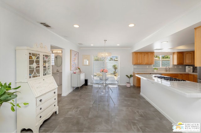 kitchen with sink, an inviting chandelier, decorative light fixtures, tile countertops, and stainless steel gas stovetop