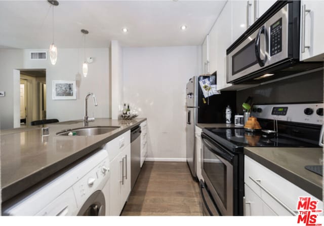 kitchen with appliances with stainless steel finishes, washer / clothes dryer, white cabinets, dark hardwood / wood-style floors, and sink