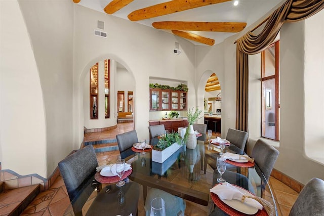 tiled dining area featuring beam ceiling