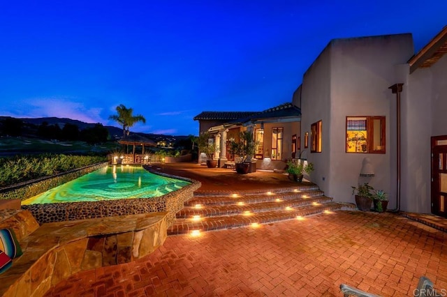 pool at dusk with a patio area