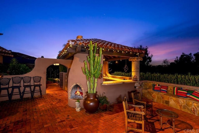 patio terrace at dusk with a bar and an outdoor fireplace