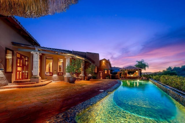 pool at dusk with a gazebo and a patio