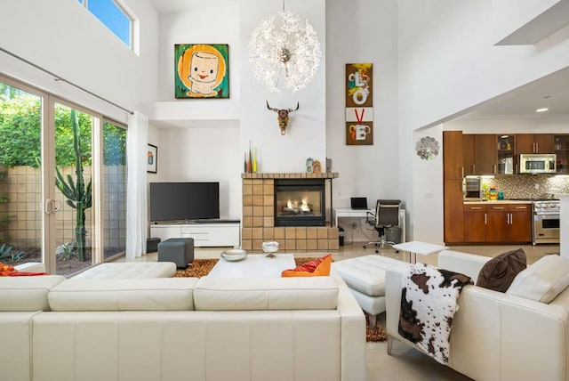 living room featuring a chandelier, a towering ceiling, and a tiled fireplace