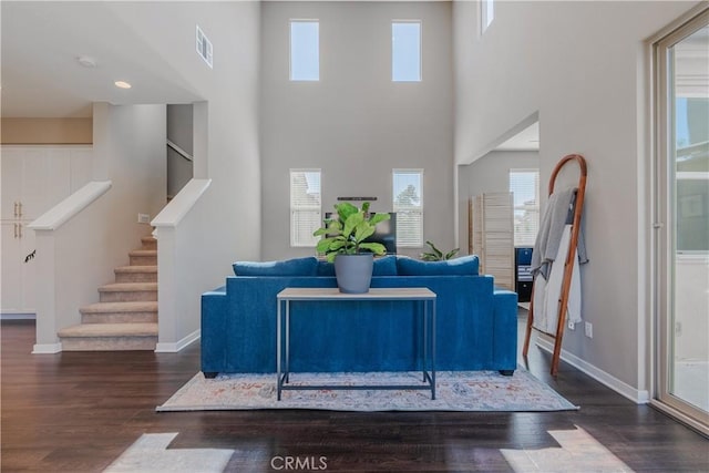 living room featuring dark hardwood / wood-style flooring and a towering ceiling