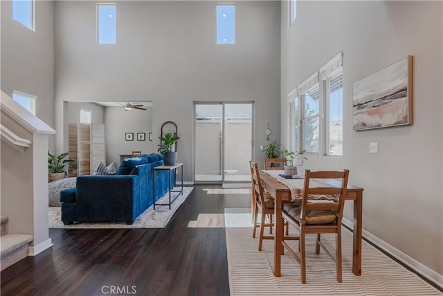 dining area with ceiling fan, a towering ceiling, and dark hardwood / wood-style floors