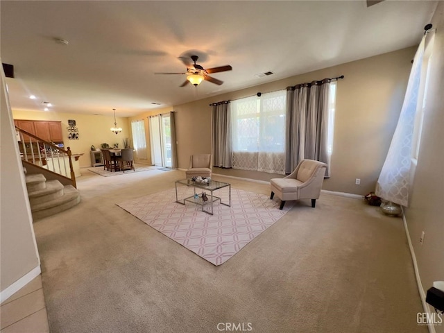 living room featuring light carpet and ceiling fan with notable chandelier