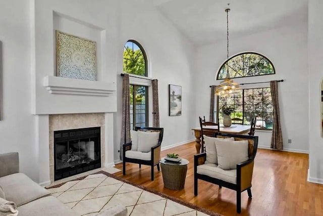 living area with a fireplace, a high ceiling, and light wood-type flooring