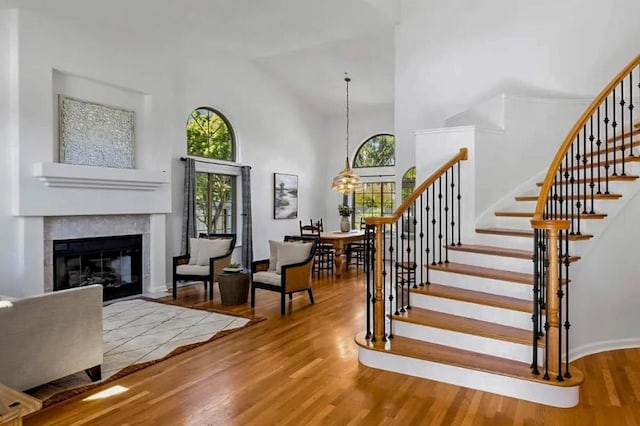 stairway featuring wood-type flooring, a tile fireplace, and a high ceiling