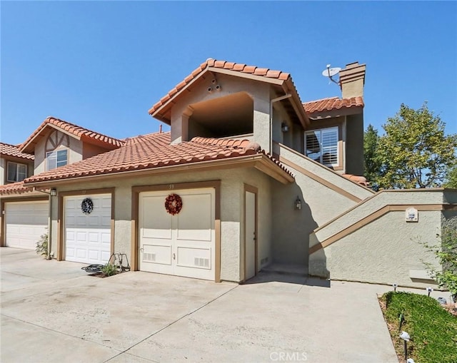 mediterranean / spanish home with concrete driveway, a chimney, an attached garage, and stucco siding