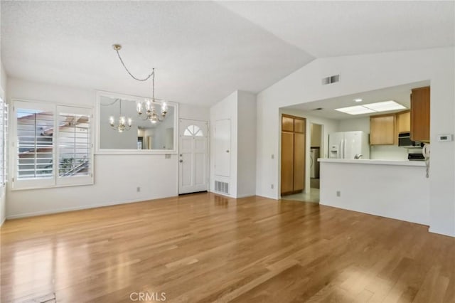 unfurnished living room with a chandelier, light hardwood / wood-style floors, and lofted ceiling