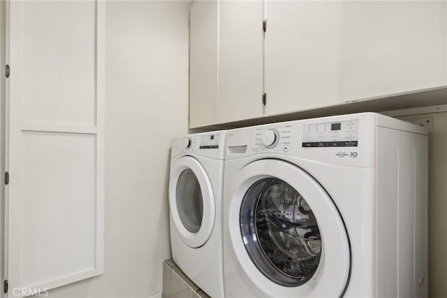 clothes washing area featuring cabinets and separate washer and dryer