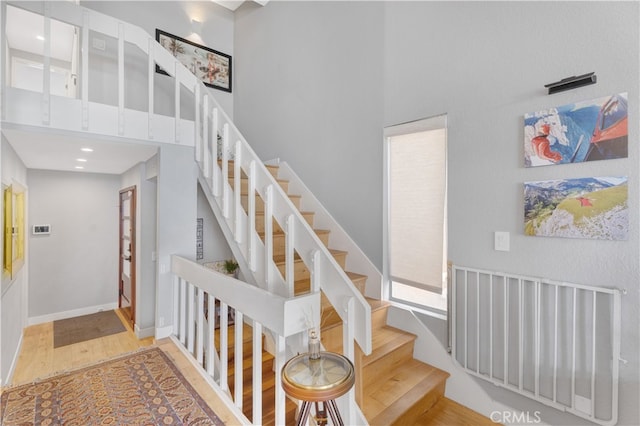 stairs featuring a towering ceiling and hardwood / wood-style floors