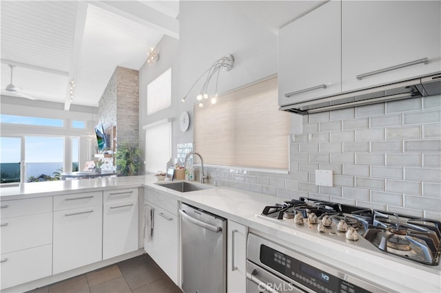 kitchen with white cabinets, dark tile patterned floors, sink, tasteful backsplash, and stainless steel appliances