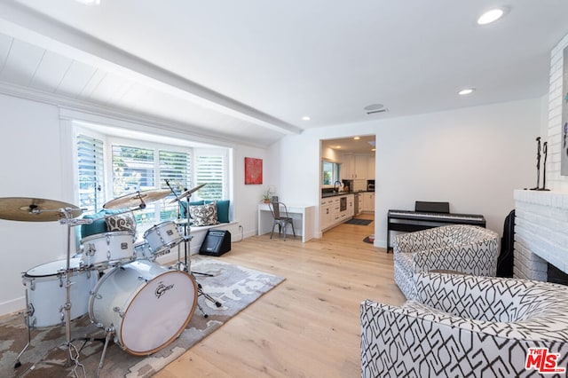 interior space featuring light hardwood / wood-style flooring, lofted ceiling with beams, a fireplace, and sink