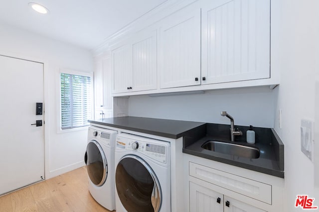 clothes washing area with light wood-type flooring, separate washer and dryer, sink, and cabinets