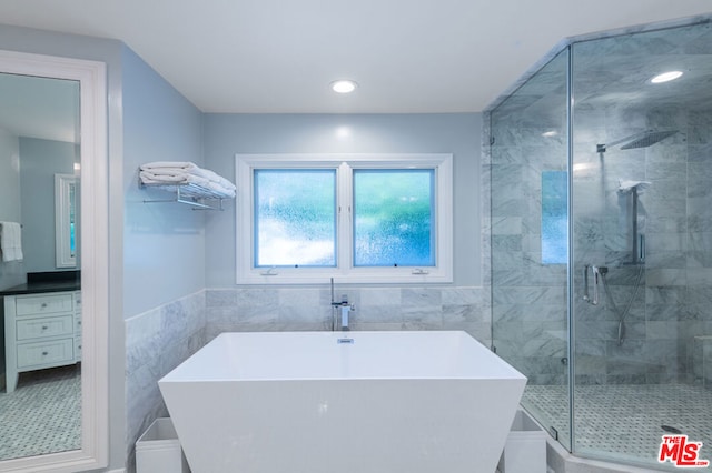 bathroom featuring tile walls, independent shower and bath, and vanity