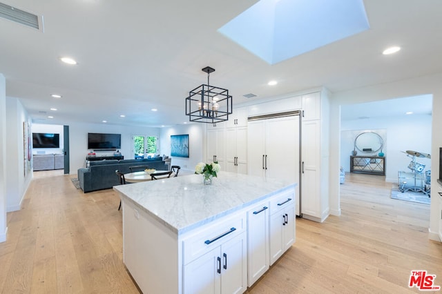 kitchen featuring white cabinets, light hardwood / wood-style flooring, pendant lighting, and a kitchen island