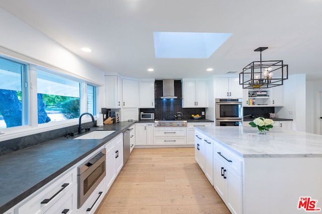 kitchen featuring white cabinets, a skylight, and sink