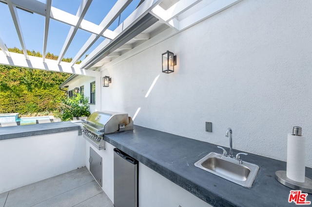 view of patio / terrace featuring a pool, area for grilling, sink, and exterior kitchen