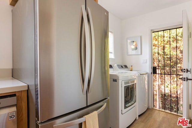 washroom featuring washing machine and clothes dryer, light hardwood / wood-style floors, and a healthy amount of sunlight