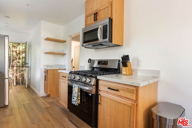 kitchen with light hardwood / wood-style flooring, tile countertops, and appliances with stainless steel finishes