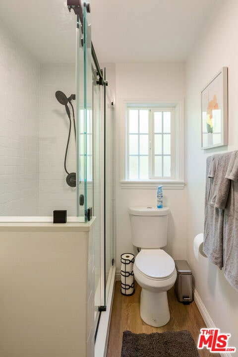 bathroom featuring wood-type flooring, an enclosed shower, and toilet