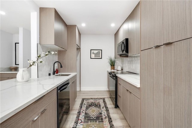 kitchen featuring tasteful backsplash, light stone countertops, light hardwood / wood-style flooring, and black appliances