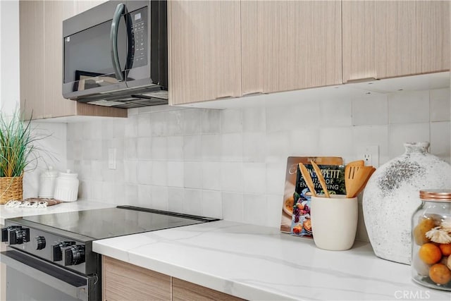 kitchen featuring light brown cabinets, electric range oven, and tasteful backsplash