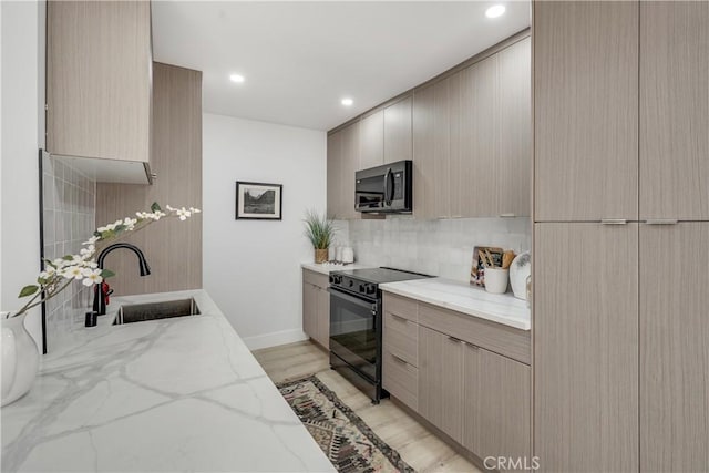 kitchen featuring black electric range oven, sink, light stone countertops, tasteful backsplash, and light hardwood / wood-style floors