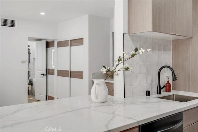 kitchen with light stone counters, sink, stainless steel dishwasher, and light brown cabinets