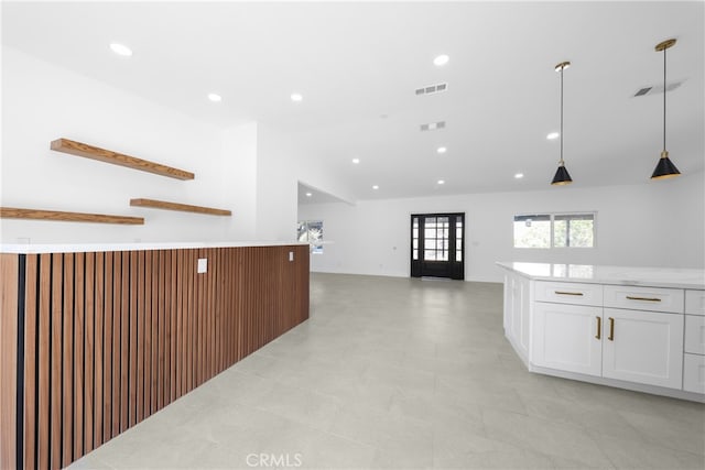 kitchen with light stone counters, white cabinets, lofted ceiling, and hanging light fixtures