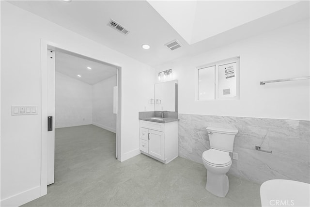 bathroom with tile walls, vanity, and toilet