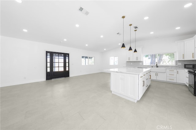 kitchen featuring black appliances, hanging light fixtures, plenty of natural light, and a kitchen island