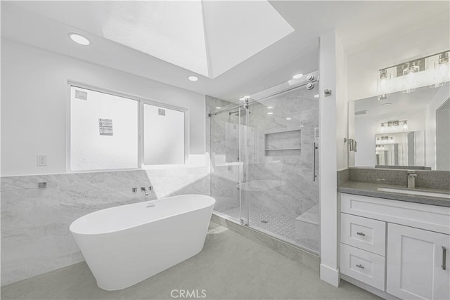 bathroom featuring independent shower and bath, vanity, and tile walls