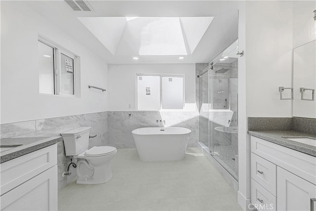 full bathroom featuring tile walls, separate shower and tub, vanity, and toilet