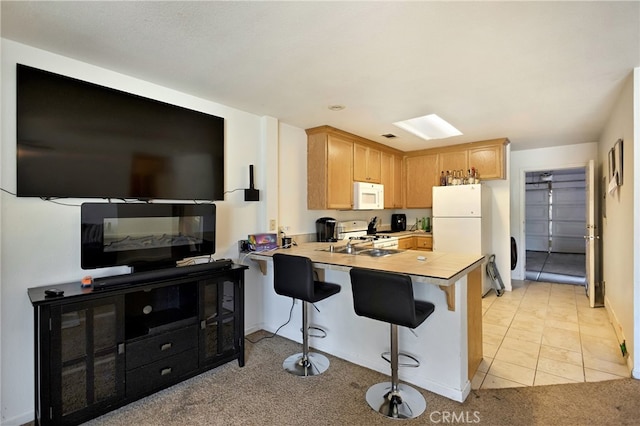 kitchen featuring a breakfast bar, kitchen peninsula, light colored carpet, white appliances, and light brown cabinets