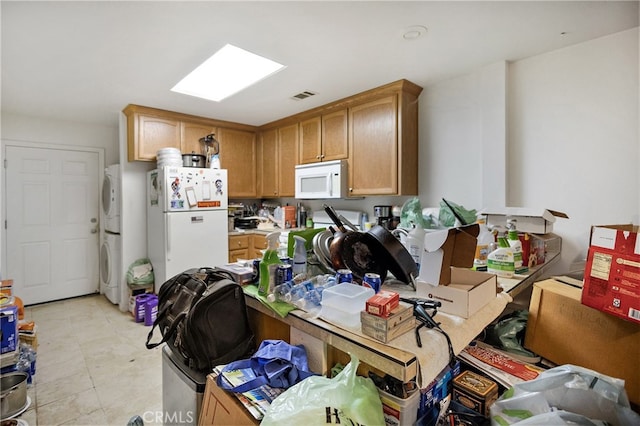 kitchen with white appliances and stacked washer and dryer