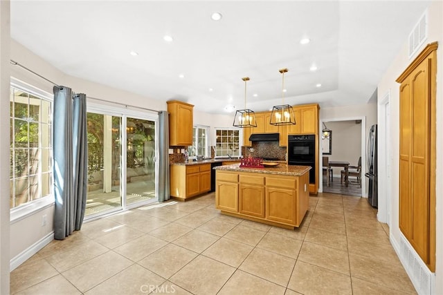 kitchen with tasteful backsplash, light stone counters, black appliances, a kitchen island, and hanging light fixtures