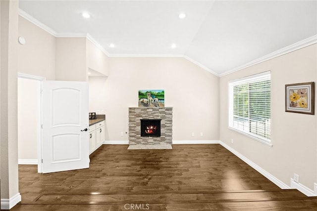 unfurnished living room featuring vaulted ceiling, a stone fireplace, crown molding, and dark hardwood / wood-style floors