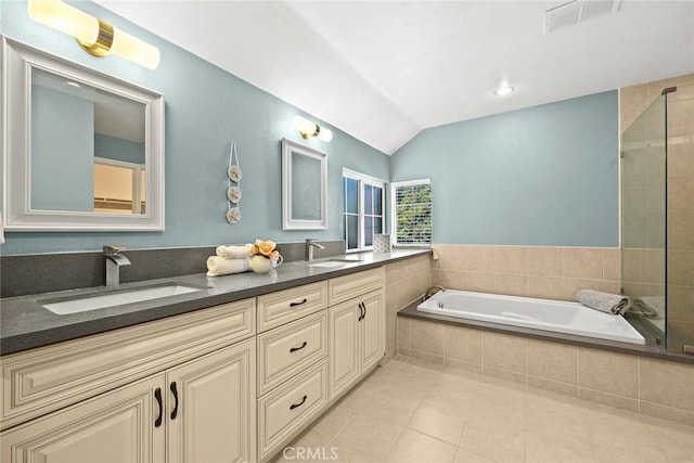 bathroom with tile patterned floors, tiled tub, vanity, and vaulted ceiling