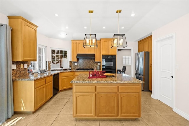 kitchen featuring light stone countertops, a center island, black appliances, and decorative light fixtures