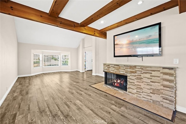 unfurnished living room with a fireplace, wood-type flooring, and lofted ceiling with beams