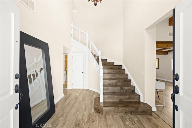 entryway featuring light hardwood / wood-style flooring and a towering ceiling